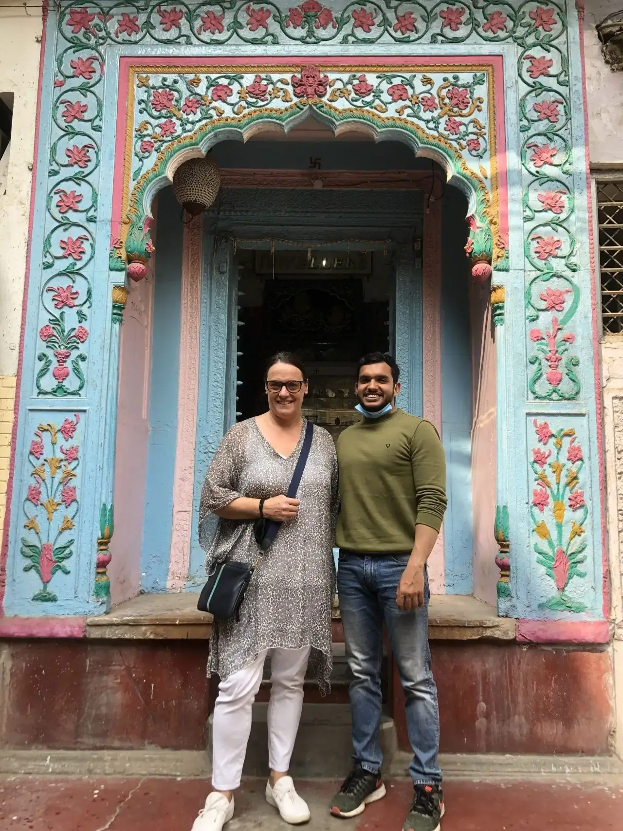 Two men standing in front of a colorful, intricately decorated doorway.