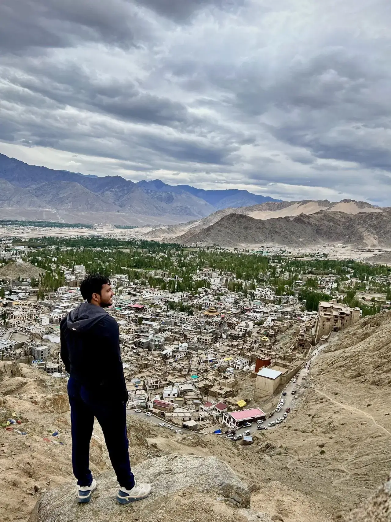 A man overlooking a sprawling cityscape with mountains in the background.